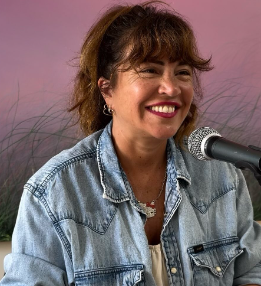 Photo d'Elsa Wolinski souriante, enregistrant un podcast devant son micro